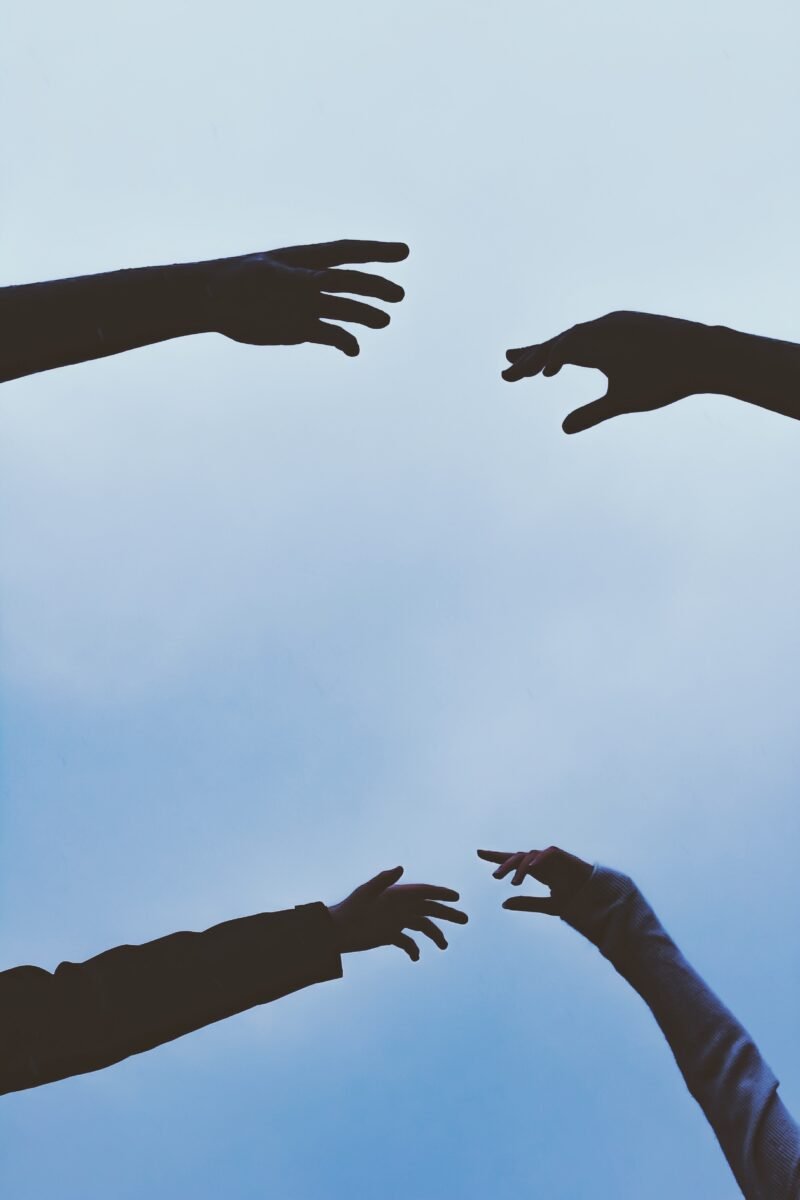 Two couples hands reaching out for each other at skyward angle for Contact